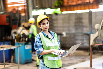 Portrait of beautiful woman serious civil engineer working with Laptop computer at industrial factory wearing uniform and hardhats. Engineering and architecture concept