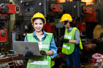 Portrait of beautiful woman serious civil engineer working with Laptop computer at industrial factory wearing uniform and hardhats. Engineering and architecture concept