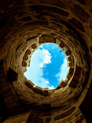 looking up to the sky or at the end of the tunnel there is a light, foreground tunnel and background the blue sky with clouds 