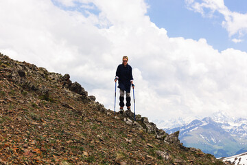 Young female tourist stands on top of a mountain