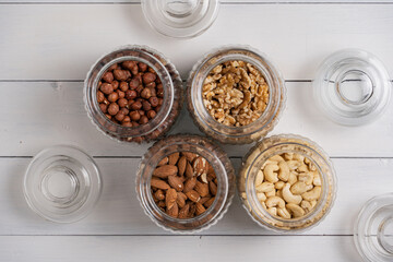 Cashew, Mandel, Walnuss und Haselnuss in Aufbewahrungsgläsern draufsicht nah auf weißem Holz