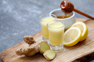Ginger shot or drink with healthy ingredients like ginger root, honey and lemon on wooden...