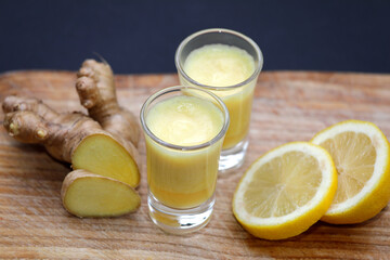 Ginger shot with fresh, healthy ingredients like ginger root and lemon with glass on wooden...