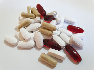 Group of red brown and white oval shape pills on a white background food suplament 
