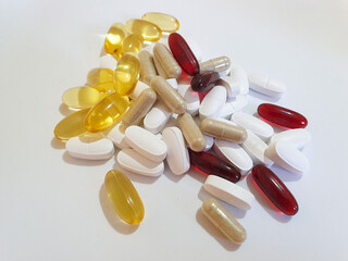 Group of red brown yellow and white oval shape pills on a white background food suplament 
