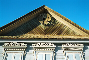 Pediment An old Russian wooden house from the times of the Russian Empire with elements of carved...