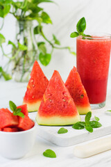 Buah Semangka or watermelon fruit, cut on wooden white chopping board, with a bowl of slices watermelon and watermelon juice. Bright mood photo on white marble background.