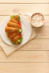 Vegan croissant sandwich and hot chocolate on wooden board top view, healthy vegetarian food concept