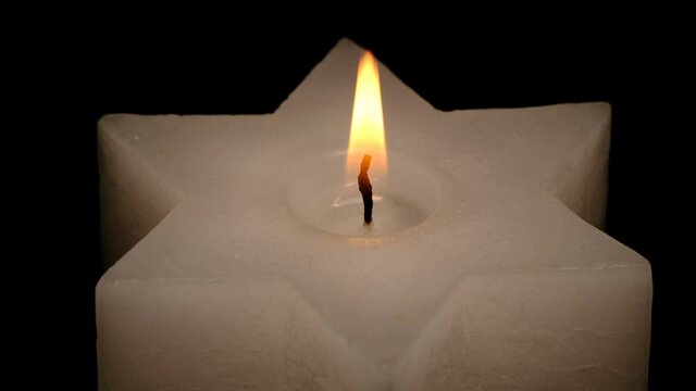 Large thick candle lit and burn on a black background high resolution video clip macro shooting close-up