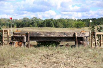 Jumping horse log obstacle on cross country course without riders as a background