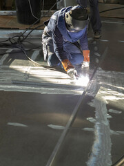 Welding at the deck of a super sailing yacht. Ship building industry. Carpenter. Shipyard.
