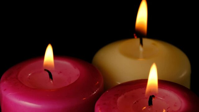 Large thick candles are lit and burn on a black background high resolution video clip macro shooting close-up
