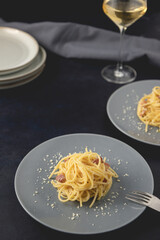 Traditional Italian dish spaghetti carbonara with bacon in a cream sauce in a plate over dark background. Close-up view with copy space.
