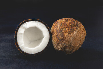 Fresh coconuts isolated on the dark background. Coconut halves. Close-up view.