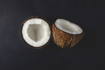 Fresh coconuts isolated on the dark background. Coconut halves. Top view, flat lay.