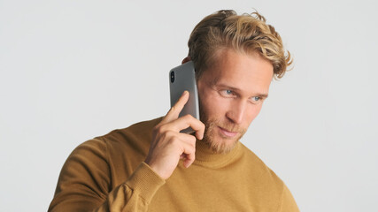 Handsome stylish bearded man talking on smartphone has important business call over white background