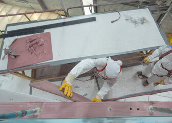 Painters putying filler and working on a super sailing yacht. Ship building industry. Shipyard.
