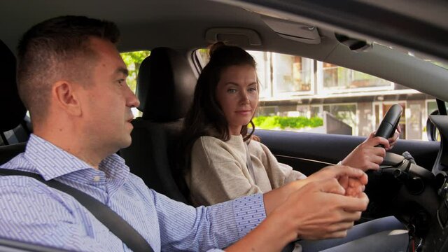 driver courses and people concept - car driving school instructor teaching young woman to drive
