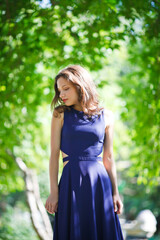 Obraz na płótnie Canvas Girl in a blue dress walks in the park