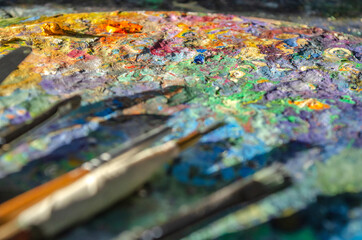 Stock Photo of a painter brushes and palette knife on a wooden palette with mixed and unmixed oil...