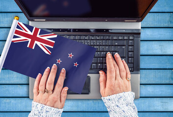 woman hands and flag of New Zealand on computer, laptop keyboard
