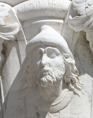 face of man with beard and long hair carved on the stone of the
