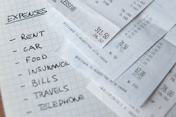 Fototapeta premium List of daily living expenses, with tax receipts next to it.