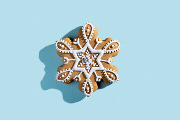 Fototapeta na wymiar Christmas pastry. Festive bakery. Winter holiday tradition. Homemade cookies. Gingerbread star figure biscuit white icing ornament isolated on blue pastel.