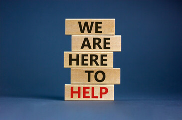 Wooden blocks with text 'we are here to help'. Beautiful grey background, copy space. Business concept.