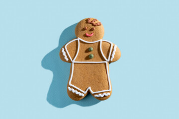 Christmas gingerbread man. Festive bakery. New Year tradition. Homemade culinary. Smiling biscuit boy figure with white icing decor isolated on blue pastel.