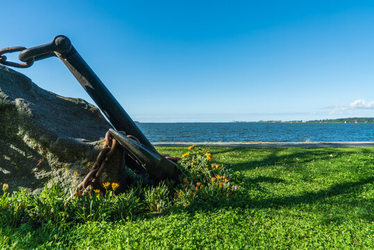 Old anchor on a meadow in front of the Baltic Sea with copy space
