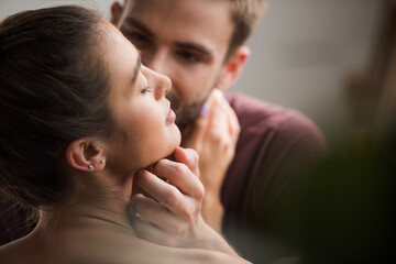 tender man touching face ow beloved girlfriend with closed eyes on blurred background