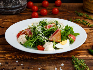 salad with tuna, egg and herbs in a plate on a wooden background