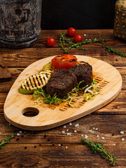 fried cuts of meat with garnish on a board for serving on a wooden background