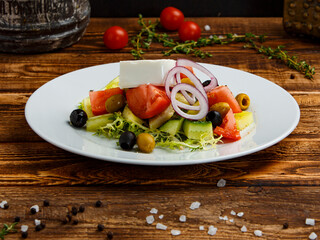 greek salad with mozzarella in a plate on a wooden background