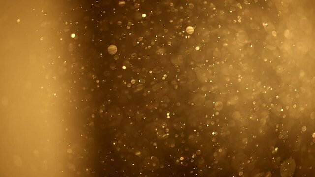 Shining golden particles abstract background. Blurred bokeh background of gold dust particles slowly floating in the air. Magical fairy background