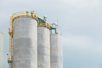 Close up and up-view shot with copy space of tall storage silo made of metal and stainless steel for stocking petroleum and petrochemical products shows the symbol of economic and industrial growth.