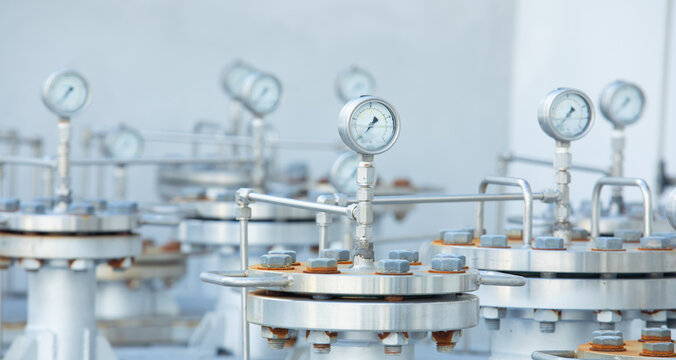 Close up and front view shot with copy space, blurred background and selective focus shot of cylinder metal tanks with pressure gauges shows safety environment equipment in petrochemical industry