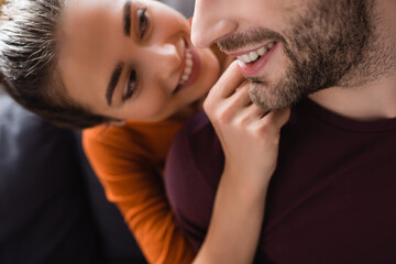 smiling woman touching face of happy man on blurred background