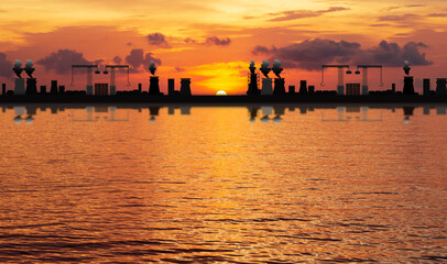 Fototapeta na wymiar silhouette of large industrial On the sea or river,Causing air pollution and Water pollution.On the sunset background.Environmental conservation concept.