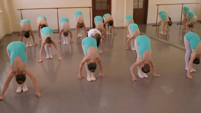 A group of children do a warm-up before a dance lesson in the ballet Studio. Ballerinas training at hall.