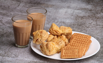 cutting masala chai or tea served with puff pastry/ khari and biscuits.