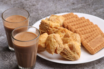 Fototapeta na wymiar cutting masala chai or tea served with puff pastry/ khari and biscuits.