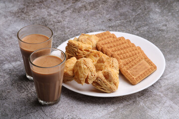 cutting masala chai or tea served with puff pastry/ khari and biscuits.