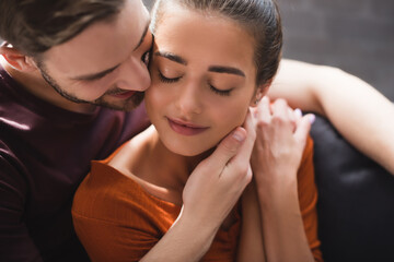 tender man touching face of beloved woman sitting with closed eyes