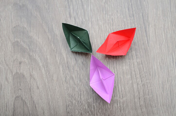 three colorful origami paper boats on wooden, top down