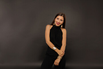 Merry young woman smiling and posing over black backdrop. Studio shot of caucasian girl laughing on black background