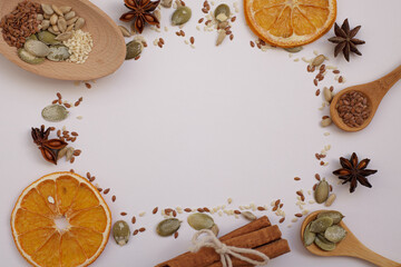 Fototapeta na wymiar Flax seeds, sesame seeds, sunflower seeds and pumpkin seeds on a white background. Around dried orange, cinnamon, star anise. The view from the top. Copy space