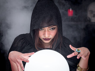 Portrait of beautiful woman fortune-teller looking at magic crystal ball for predict future....