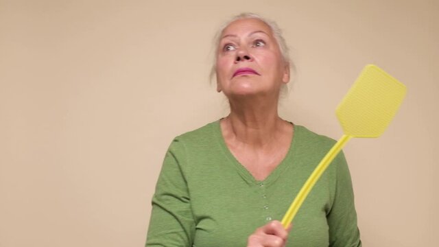 Senior caucasian woman holding fly swatter